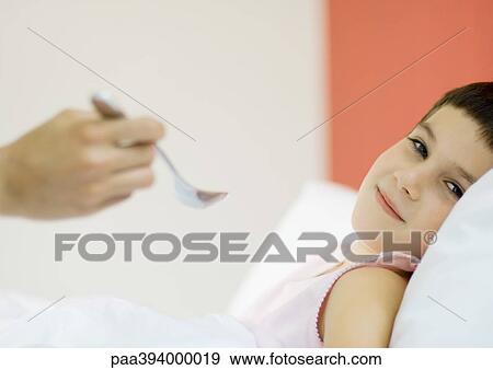 Child in bed, hand approaching child's mouth with spoon View Large Photo Image Stock Photo - Child in bed, hand approaching child's mouth with spoon. Fotosearch