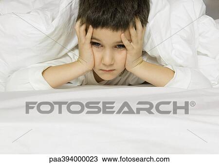 Child lying in bed, holding head View Large Photo Image Stock Image - Child lying in bed, holding head. Fotosearch