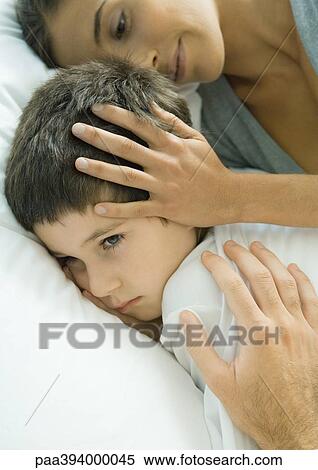 Child lying in bed, parent's hands on head and shoulder View Large Photo Image Stock Photography - Child lying in bed, parent's hands on head and shoulder. Fotosearch