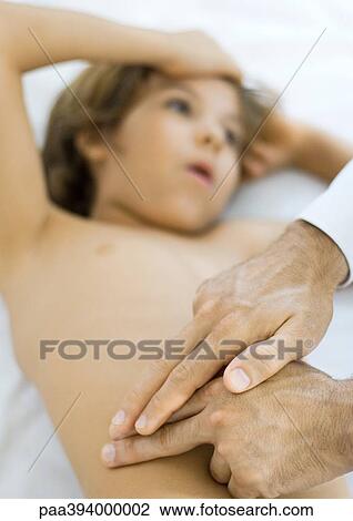 Stock Image - Doctor feeling boy's stomach. Fotosearch