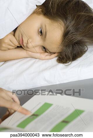 Girl lying in bed, listening to mother read from book View Large Photo Image Stock Image - Girl lying in bed, listening to mother read from book. Fotosearch