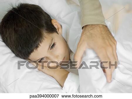 Stock Photo - Man's hand putting blankets on child. Fotosearch