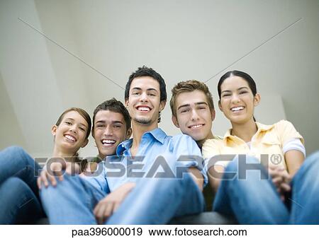 Group of teens sitting side by side, smiling at camera, low angle view View Large Photo Image Stock Photo - Group of teens sitting side by side, smiling at camera, low angle view. Fotosearch