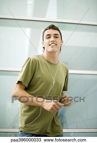 Stock Image - Teen boy listening to earphones, dancing. Fotosearch