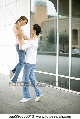 Stock Image - Teen boy picking up girlfriend. Fotosearch