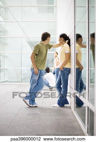 Stock Image - Teen couple leaning against wall. Fotosearch