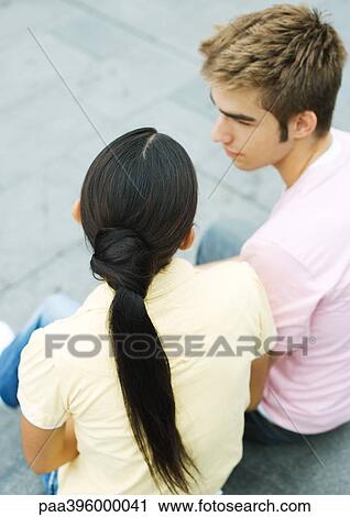 Stock Image - Teen couple sitting together, high angle view. Fotosearch