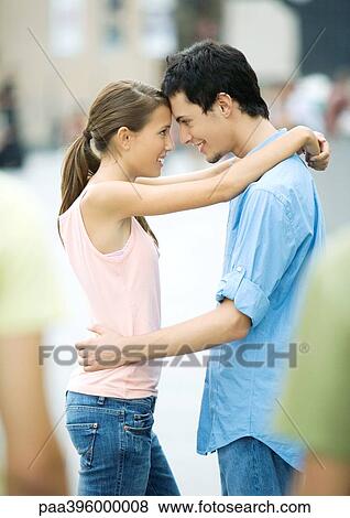 Stock Photo - Teen couple standing with foreheads together and arms around each other. Fotosearch