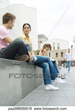 Teens sitting outdoors in urban area View Large Photo Image Stock Photograph - Teens sitting outdoors in urban area. Fotosearch