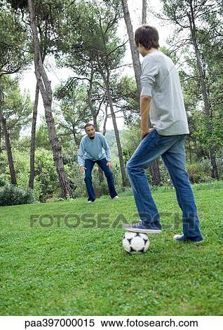 Stock Photography - Mature man and teenage boy playing soccer. Fotosearch