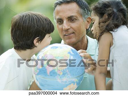 Picture - Mature man looking at globe with grandchildren. Fotosearch