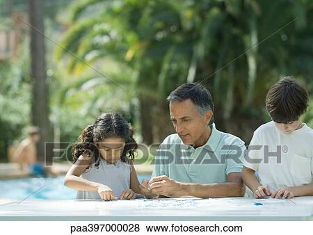Mature man putting together puzzle with grandchildren View Large Photo Image Stock Photo - Mature man putting together puzzle with grandchildren. Fotosearch