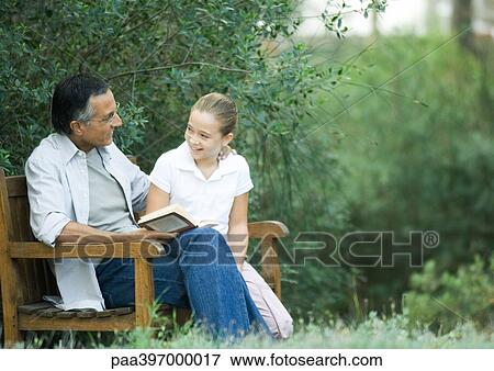 Mature man reading with granddaughter outdoors View Large Photo Image Stock Photo - Mature man reading with granddaughter outdoors. Fotosearch