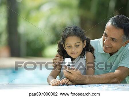 Mature man showing granddaughter cell phone View Large Photo Image Stock Image - Mature man showing granddaughter cell phone. Fotosearch