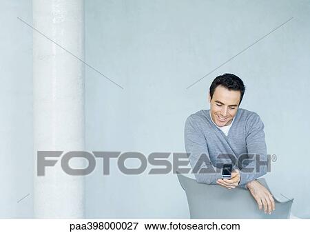 Man looking at cell phone, smiling View Large Photo Image Stock Photo - Man looking at cell phone, smiling. Fotosearch