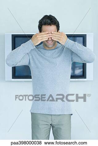 Man standing in front of widescreen TV on wall, hands covering eyes View Large Photo Image Stock Photo - Man standing in front of widescreen TV on wall, hands covering eyes. Fotosearch