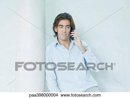 Man using cell phone, leaning against column View Large Photo Image Picture - Man using cell phone, leaning against column. Fotosearch