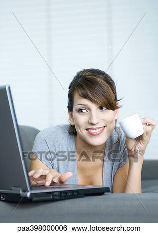 Woman drinking coffee and using laptop View Large Photo Image Stock Photograph - Woman drinking coffee and using laptop. Fotosearch