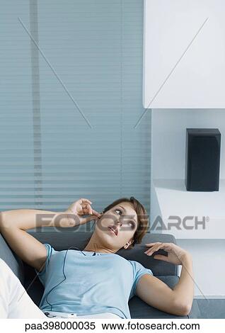 Woman lying on sofa, putting in earphones View Large Photo Image Stock Photography - Woman lying on sofa, putting in earphones. Fotosearch