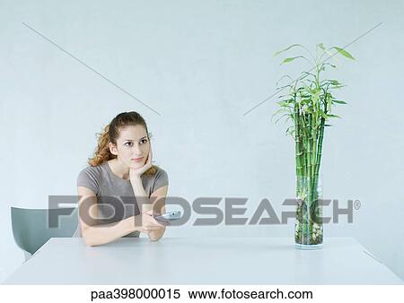 Woman sitting at table, pointing remote control View Large Photo Image Stock Photography - Woman sitting at table, pointing remote control. Fotosearch