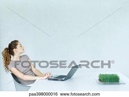 Woman sitting at table with laptop View Large Photo Image Stock Photograph - Woman sitting at table with laptop. Fotosearch