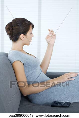 Woman sitting on sofa, looking at fingernails, wireless phone by side View Large Photo Image Stock Image - Woman sitting on sofa, looking at fingernails, wireless phone by side. Fotosearch