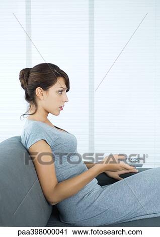 Woman sitting on sofa, pointing remote control, side view View Large Photo Image Stock Image - Woman sitting on sofa, pointing remote control, side view. Fotosearch