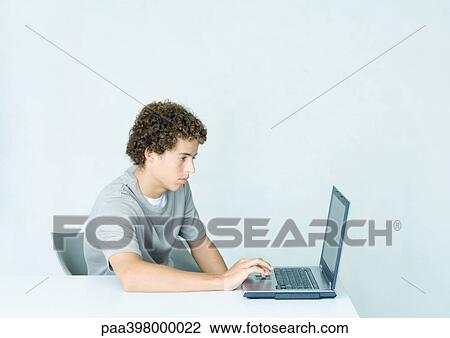 Young man using laptop computer at table View Large Photo Image Stock Image - Young man using laptop computer at table. Fotosearch
