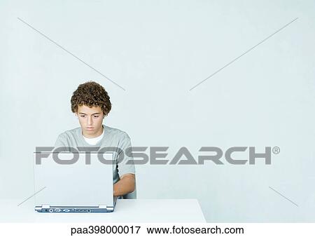 Stock Photo - Young man using laptop, front view. Fotosearch