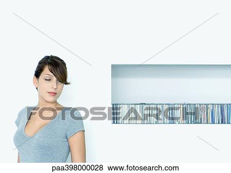 Stock Photo - Young woman next to shelf of CDs. Fotosearch