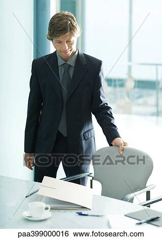 Businessman pulling seat out in office View Large Photo Image Stock Photograph - Businessman pulling seat out in office. Fotosearch