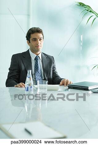 Businessman sitting at table with closed laptop and bottle of mineral water View Large Photo Image Picture - Businessman sitting at table with closed laptop and bottle of mineral water. Fotosearch