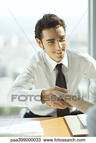 Man shaking hands across table View Large Photo Image Stock Image - Man shaking hands across table. Fotosearch