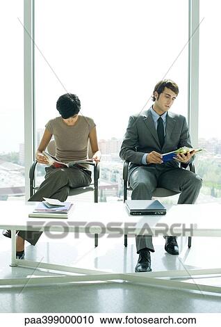 Professional man and woman sitting in lobby, looking at magazines View Large Photo Image Stock Image - Professional man and woman sitting in lobby, looking at magazines. Fotosearch
