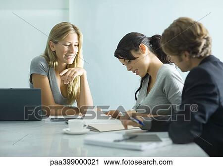 Three adults sitting at table, looking over document View Large Photo Image Stock Image - Three adults sitting at table, looking over document. Fotosearch