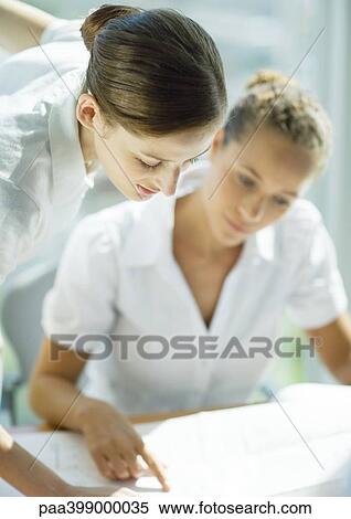 Two female professionals looking at blueprints together View Large Photo Image Stock Photography - Two female professionals looking at blueprints together. Fotosearch