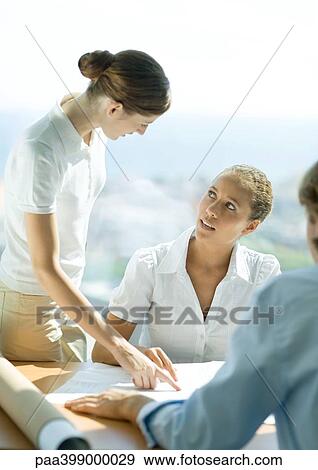 Woman pointing to blueprints and speaking to second woman View Large Photo Image Stock Photo - Woman pointing to blueprints and speaking to second woman. Fotosearch