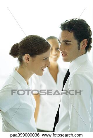 Young professional couple talking, second woman standing in background View Large Photo Image Stock Photograph - Young professional couple talking, second woman standing in background. Fotosearch