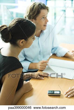Young professional couple with contract, man speaking and looking out of frame View Large Photo Image Stock Photograph - Young professional couple with contract, man speaking and looking out of frame. Fotosearch