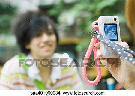 Picture - Teenage boy having photo taken with cell phone. Fotosearch