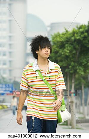 Stock Image - Teenage boy walking in urban setting. Fotosearch