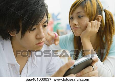 Teenage couple, boy playing video game while girl pesters him View Large Photo Image Stock Photo - Teenage couple, boy playing video game while girl pesters him. Fotosearch