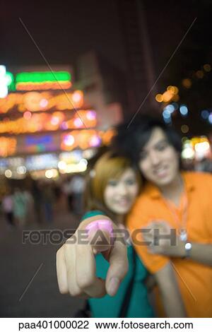 Stock Image - Teenage couple, focus on girl's finger pointing at camera. Fotosearch