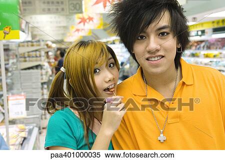 Teenage couple in grocery store, girl eating lollipop View Large Photo Image Stock Photography - Teenage couple in grocery store, girl eating lollipop. Fotosearch