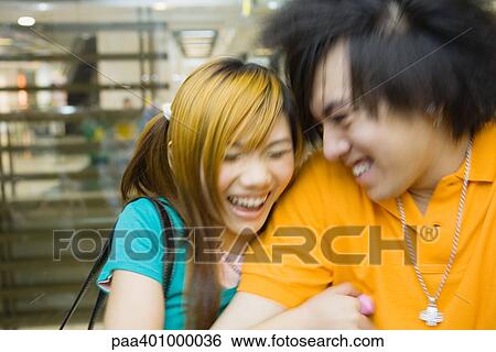 Stock Photograph - Teenage couple laughing, blurred motion. Fotosearch
