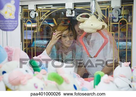 Teenage couple looking at toy grabbing game in video arcade View Large Photo Image Stock Photograph - Teenage couple looking at toy grabbing game in video arcade . Fotosearch