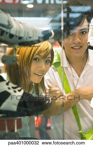Stock Image - Teenage couple looking in shoe shop window. Fotosearch