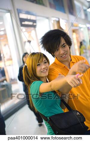 Teenage couple pointing out of frame View Large Photo Image Picture - Teenage couple pointing out of frame. Fotosearch