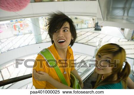 Teenage couple riding escalator in mall, high angle view View Large Photo Image Stock Photography - Teenage couple riding escalator in mall, high angle view. Fotosearch