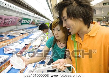 Stock Image - Teenage couple shopping in grocery store. Fotosearch
